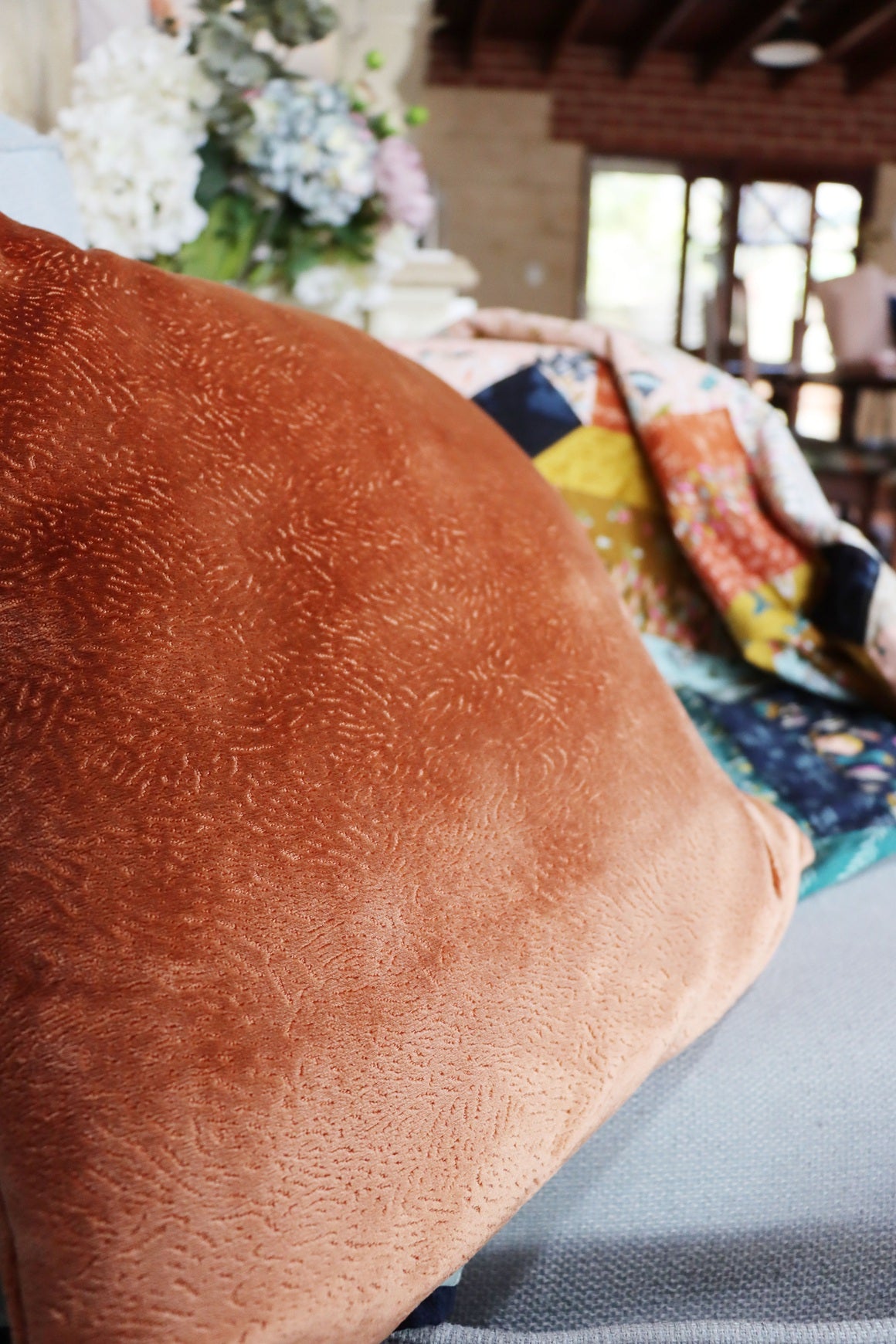 Close-up of a brown textured velvet cushion cover with a blurred indoor background