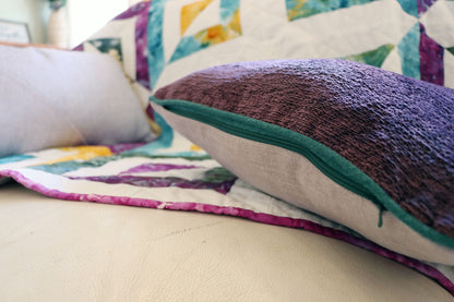 Colourful quilt with textured chenille cushion cover with contrasting piping on a sofa