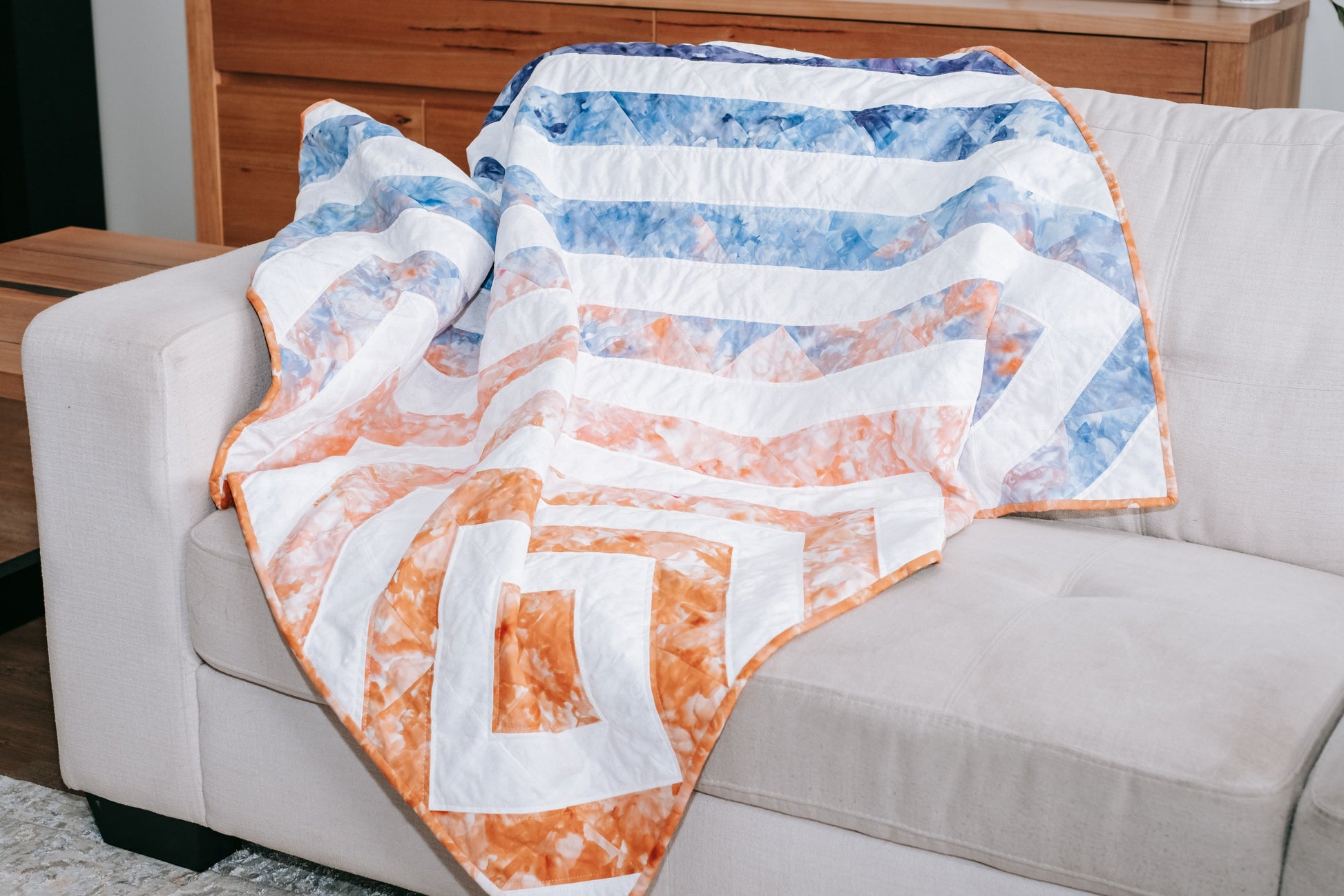 Lifestyle photo of geometric handmade quilt with mink backing on sofa