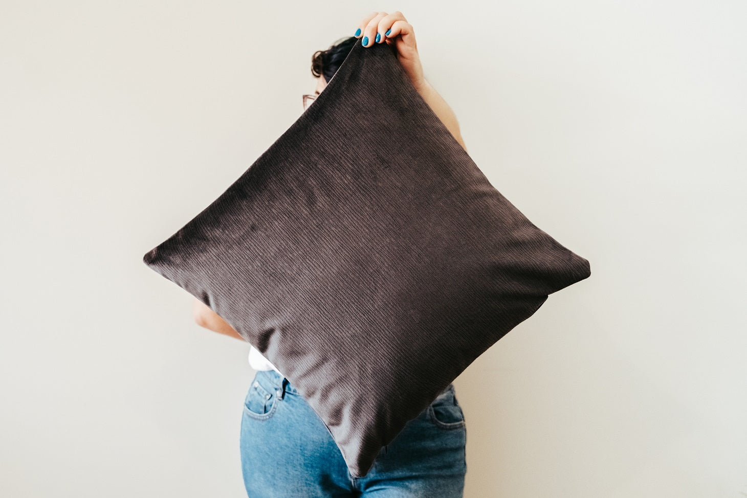 Person holding grey velvet cushion from quilt and cushion bundle
