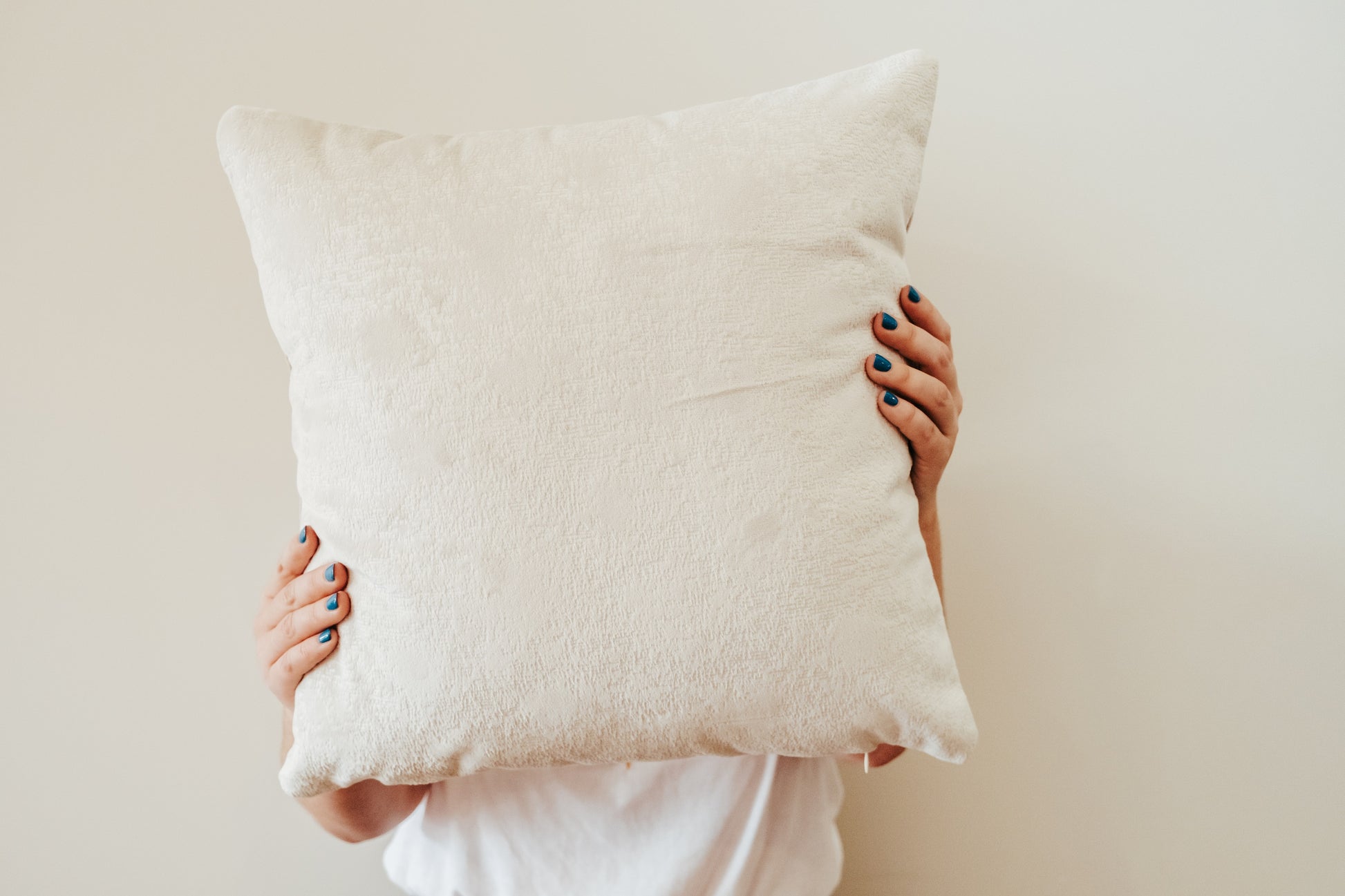 Person holding white velvet cushion from quilt and cushion bundle