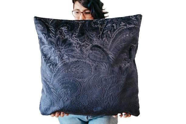 Person holding a black paisley textured velvet cushion cover