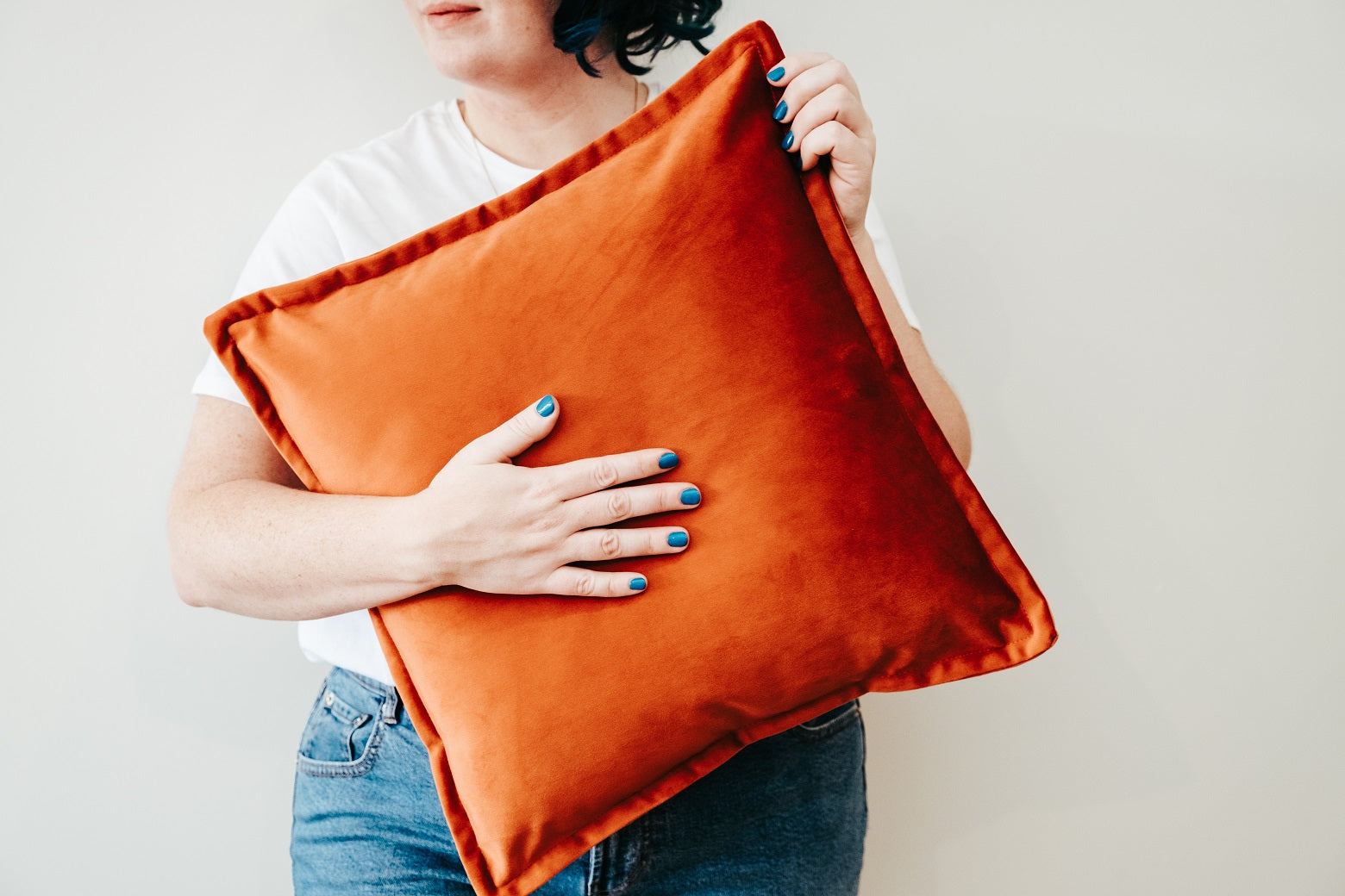 Person holding orange velvet cushion from quilt and cushion bundle