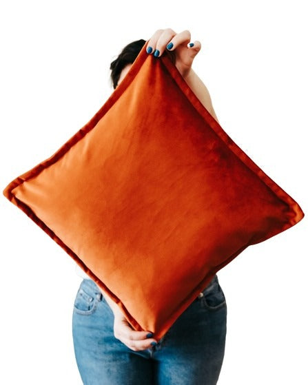 Close up person holding orange velvet cushion cover with flange edging