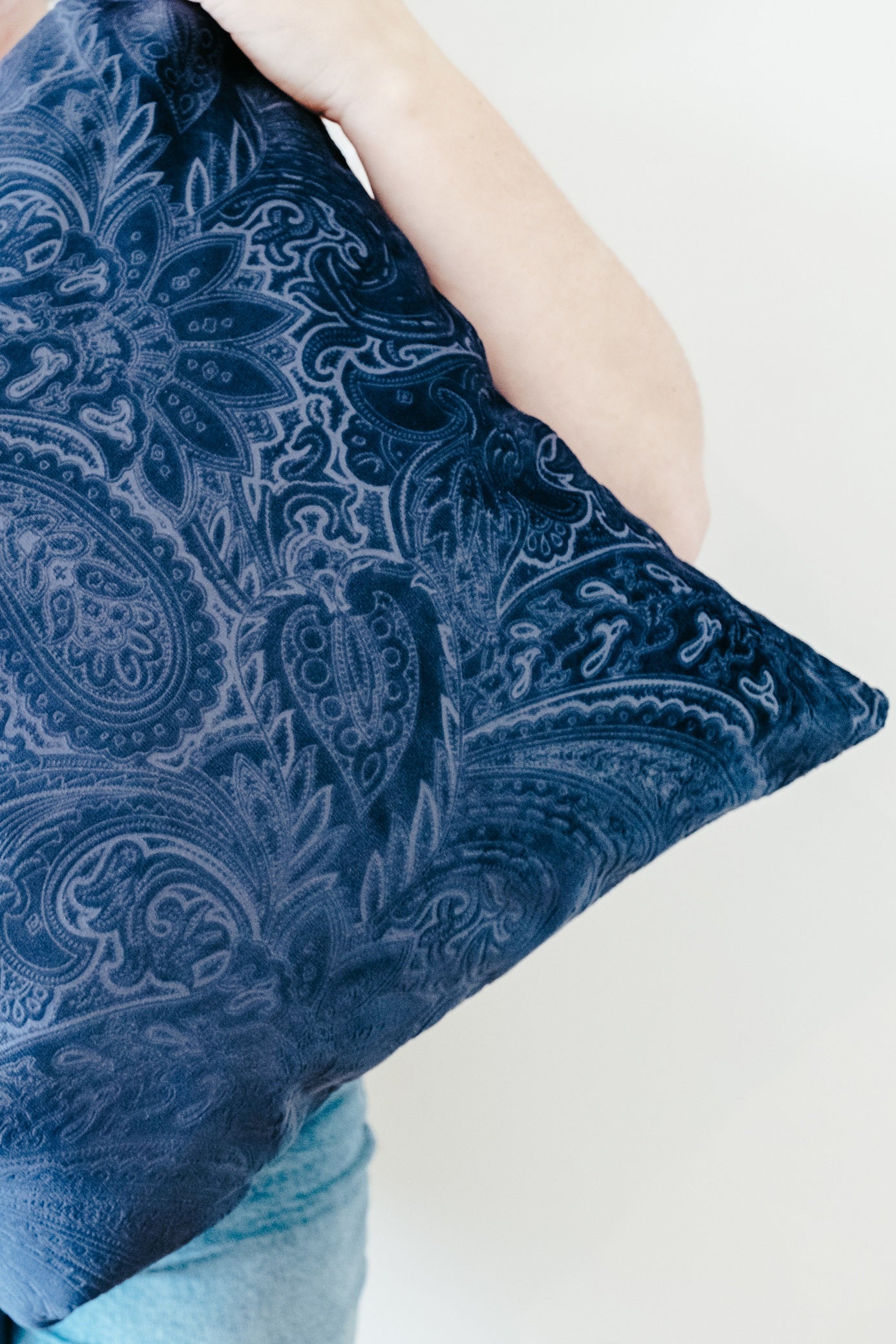 Close up of person holding navy textured velvet cushion cover