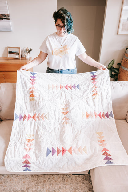 Person holding flying geese handmade quilt with mink backing