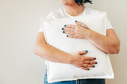 Person holding white velvet cushion from quilt and cushion bundle