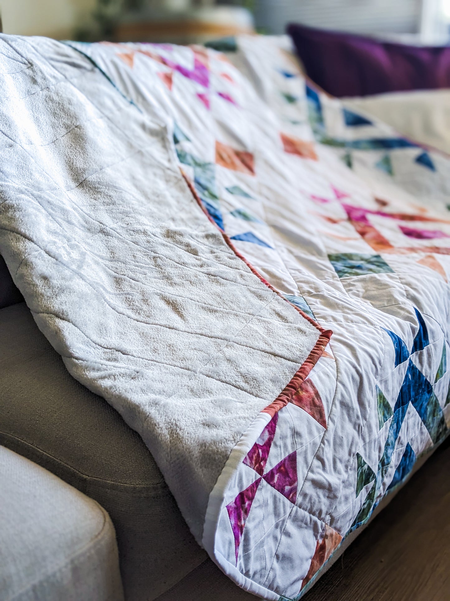 Close up of handmade boho quilt with mink backing on couch